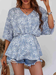 Light blue abstract print cinched waist blouse with V-neck and short sleeves.