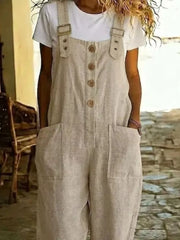 Rustic-button wide leg romper in beige with pockets and adjustable straps, worn over a white tee.