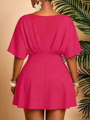 Plus-size pink mini dress with V-neck, dolman sleeves, and flared skirt.