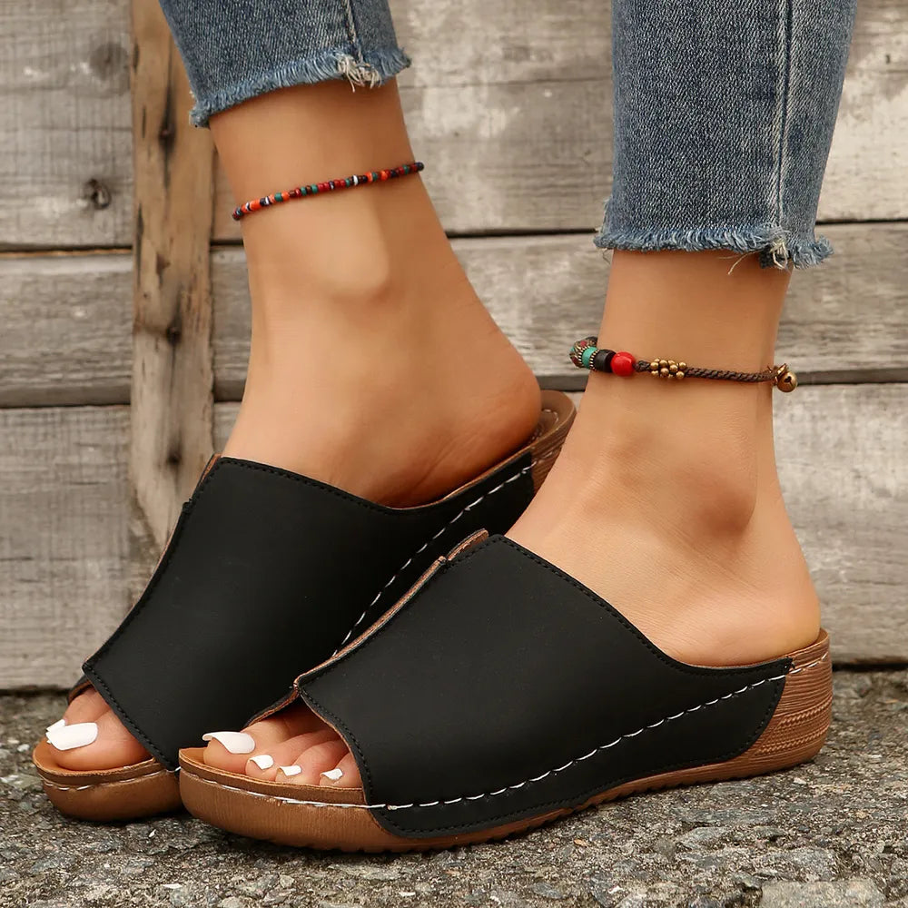 Black wedge mules with stitched edge detail and open toe.
