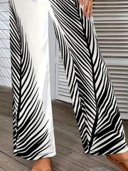 Palm print palazzo trousers in black and white, featuring a wide leg and split hem.