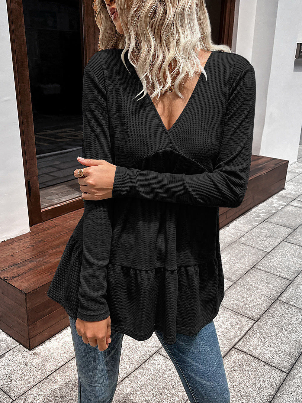 Black waffle knit peplum top with V-neck and long sleeves.