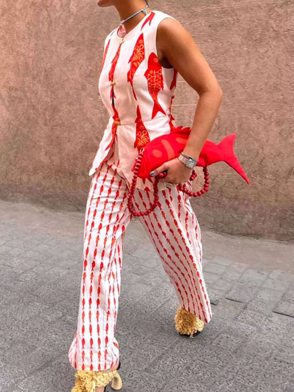 Red fish-print sleeveless button-up top and striped pants set with gold buttons.