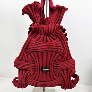 Textured knit medium backpack in burgundy with drawstring closure and unique ribbed pattern.