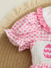 Pink gingham baby one-piece with smocked white bodice and embroidered egg detail.