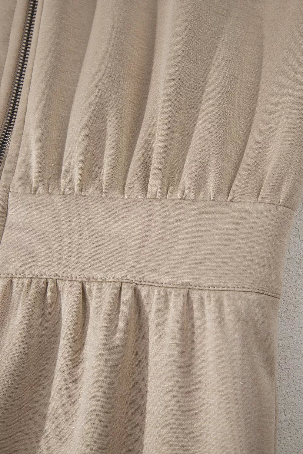 Chic collared zip front romper in beige with ruched detailing and a cinched waist.