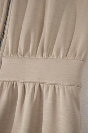 Chic collared zip front romper in beige with ruched detailing and a cinched waist.