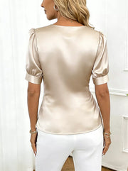 Ivory satin blouse with surplice V-neck and puffed short sleeves.