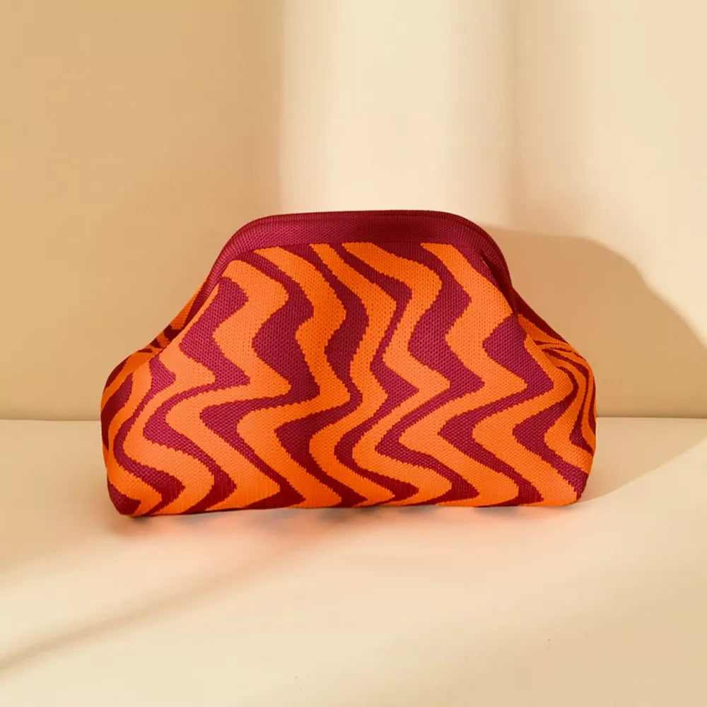 Vibrant knit clutch bag with striking orange and burgundy zig-zag stripes.