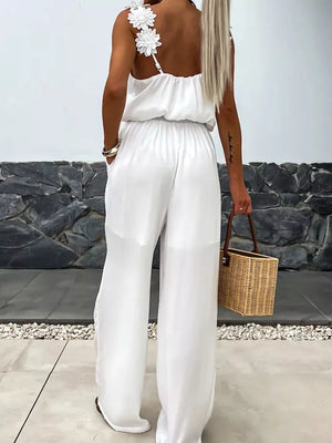 White wide-leg jumpsuit with floral applique straps and blouson waist.