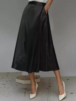 Black satin A-line midi skirt with pockets and a flowing silhouette.