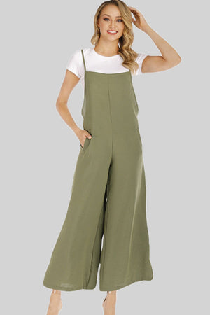 Sage culotte overalls with slender straps and wide legs, worn over a white t-shirt.