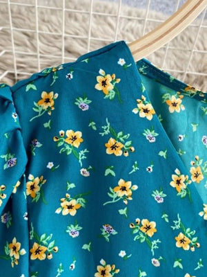 Teal floral midi dress with V-neck and short sleeves, featuring a yellow and purple floral print.