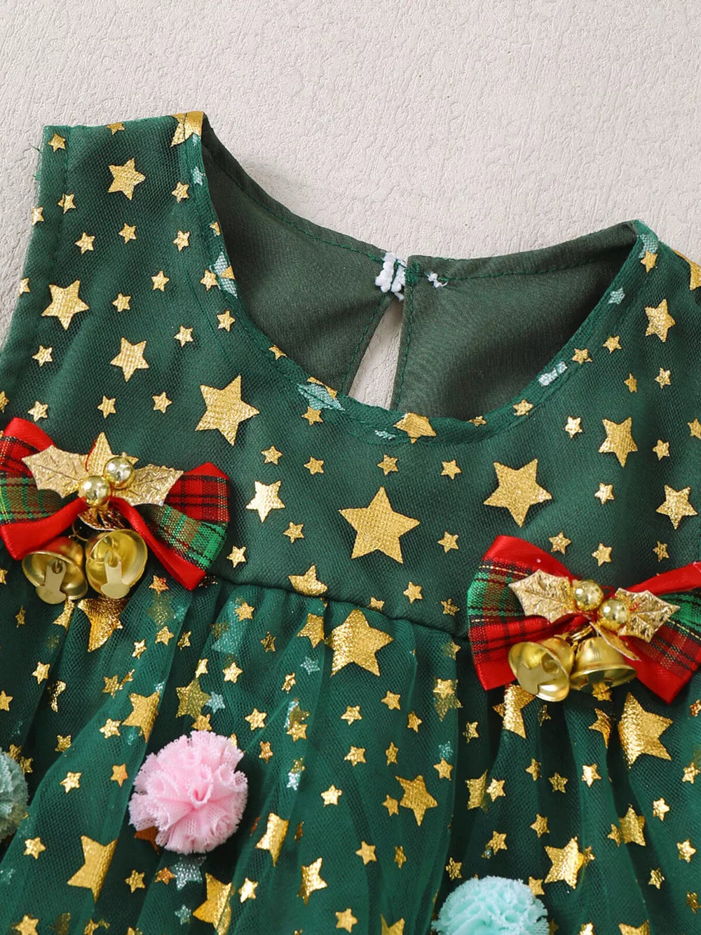 Green star print tulle baby dress with red plaid bows, bells, and pom-poms.