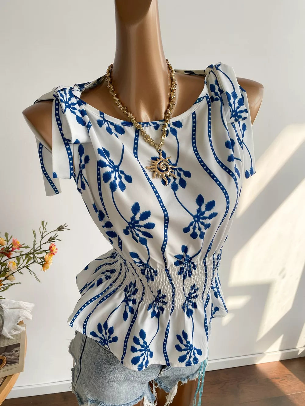 Botanical print smocked shoulder blouse with tie details and a boat neckline.