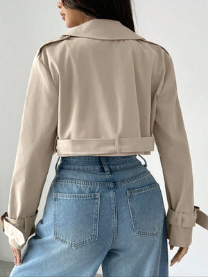 Beige cropped double-breasted trench coat with belt and adjustable cuffs.
