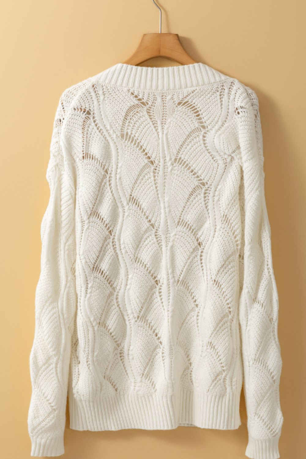 Openwork knit V-neck pullover in ivory acrylic with a wave pattern.