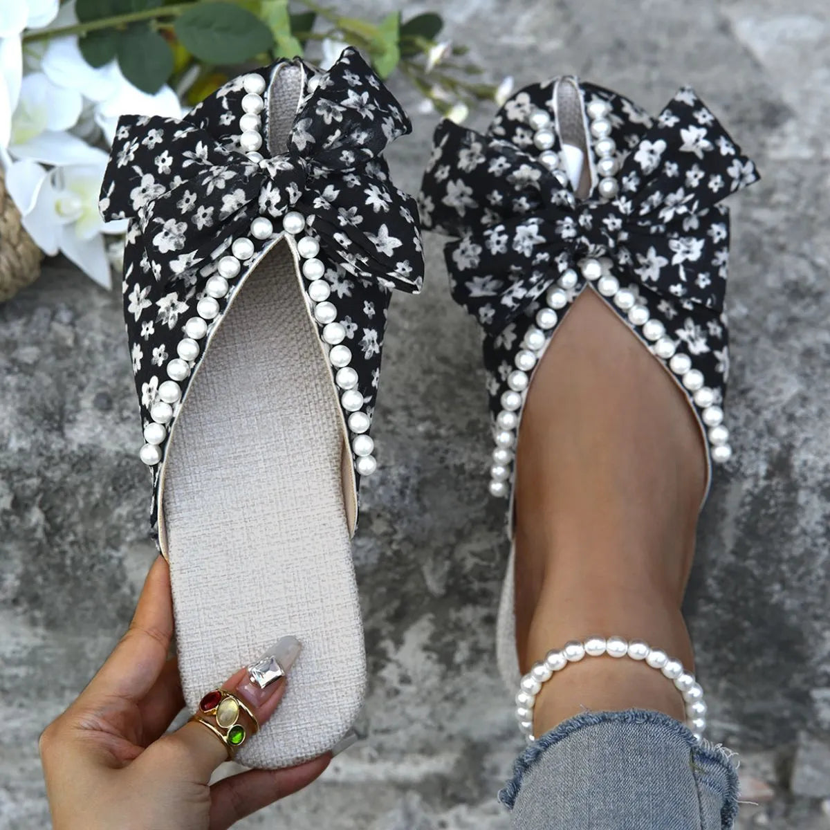 Floral bow pearl embellished slides with black floral pattern and pearl trim.