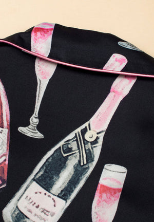 Black silk pajama set with champagne print and pink piping detail.