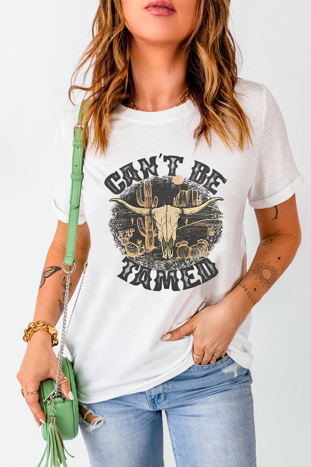 White cotton blend graphic tee with "Can't Be Tamed" text and bull skull desert graphic