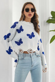 White acrylic cropped sweater with blue butterfly intarsia and frayed hem detail.