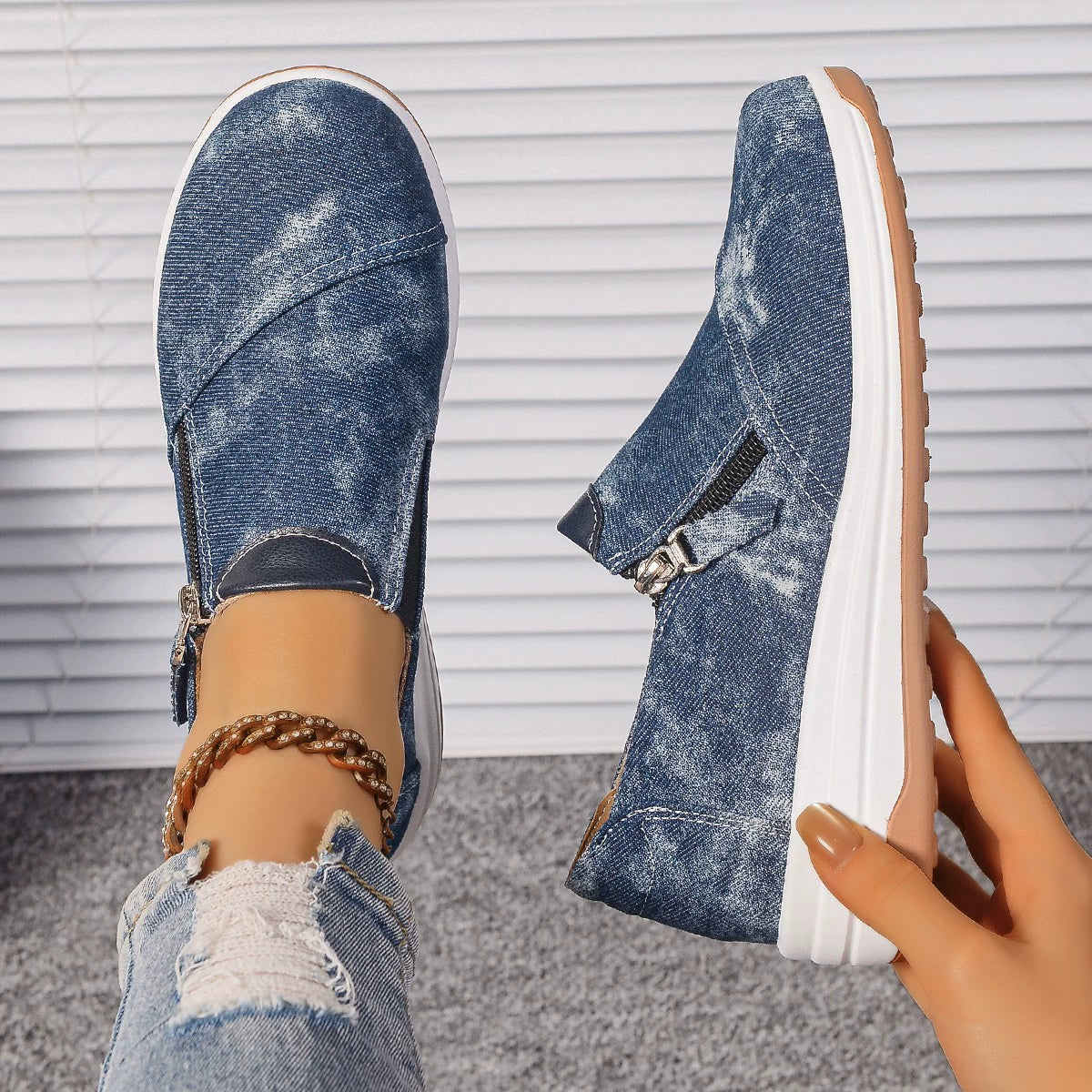 Blue denim slip-on sneakers with side zippers and a chunky white sole.