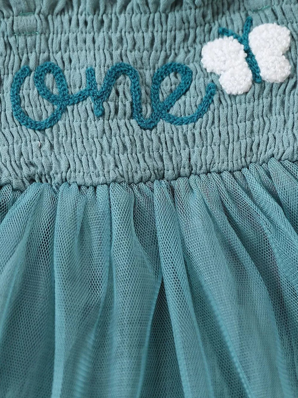 Sea blue smocked baby bodysuit with embroidered "one" and butterfly detail, and tulle skirt.