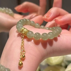 Delicate 18k gold-plated bead bracelet with gold charm and bells on a wrist.