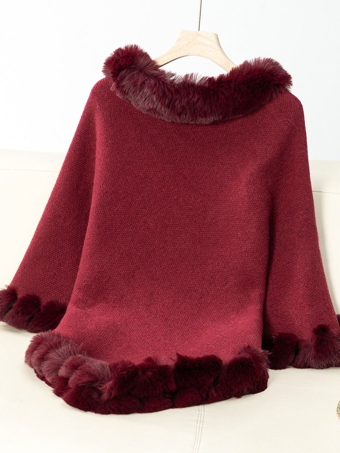 Burgundy knit poncho with faux fur trim at neckline and hem.