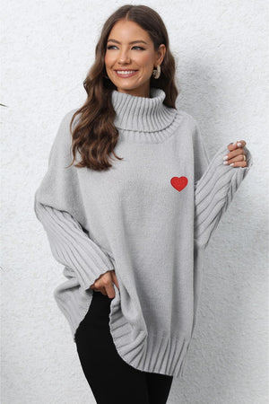 Light gray batwing knit turtleneck sweater with red heart embroidery and ribbed sleeves.