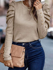 Beige knit top with gathered puff sleeves and gold button details on the cuffs.