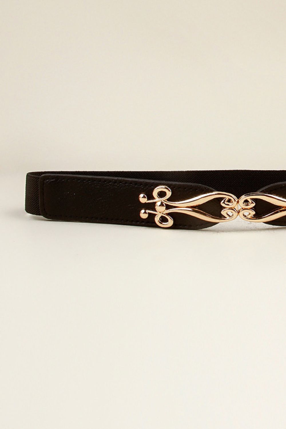 Black elastic belt with a sculpted gold alloy clasp.