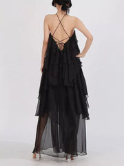 Black ruffled halter maxi dress with crisscross back straps and tiered skirt.