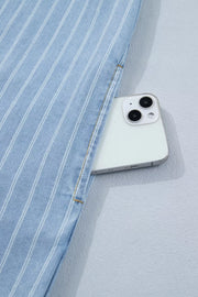 Light blue vertically striped denim mini dress with a pocket holding a smartphone.