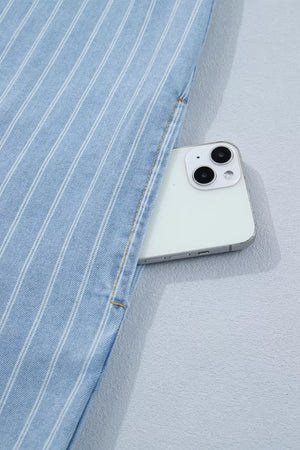 Light blue vertically striped denim mini dress with a pocket holding a smartphone.