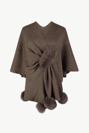 Taupe knit cape with fur trim and pom-poms.