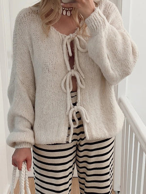 Beige knit cardigan with balloon sleeves and lace-up front detail.