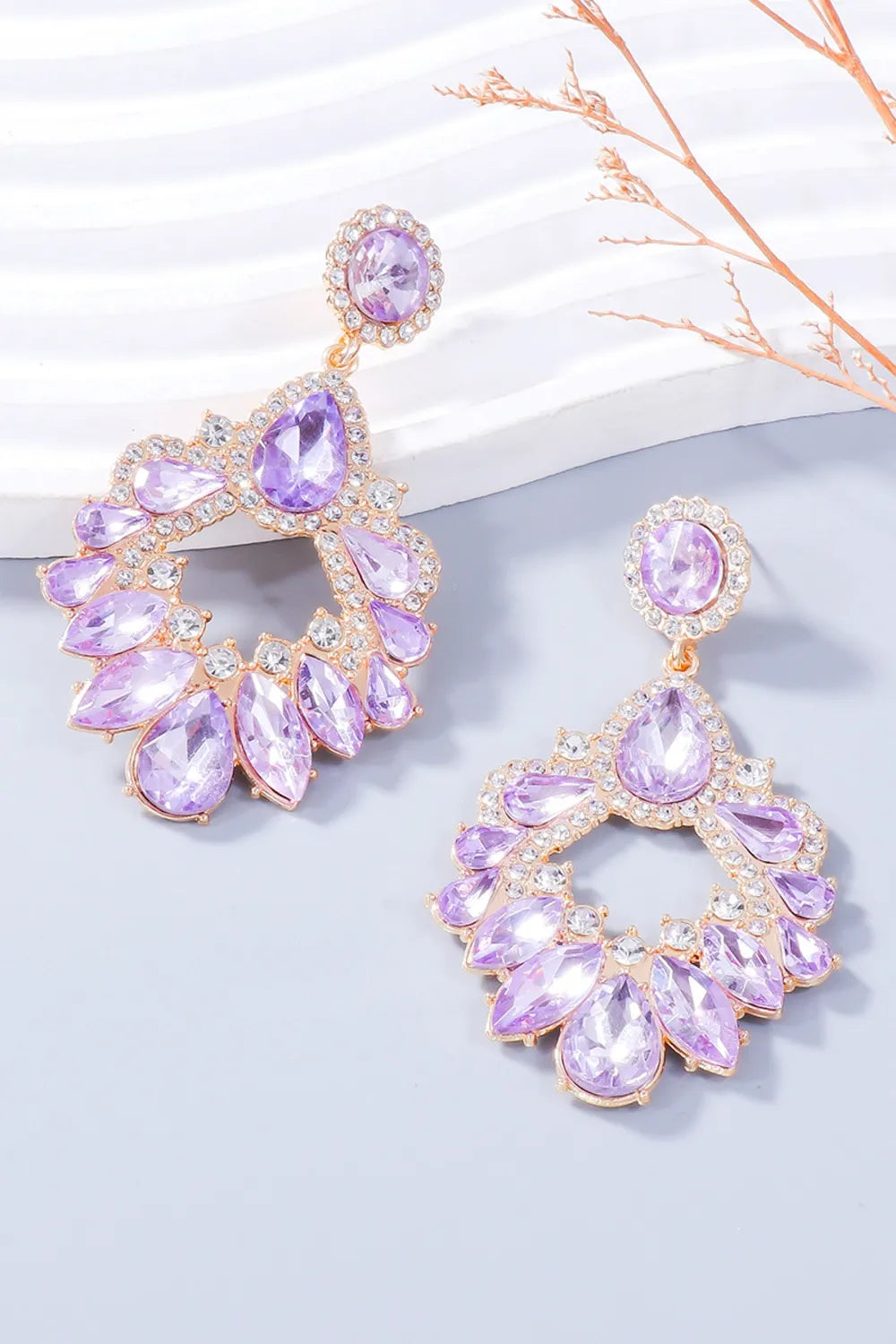 Floral-inspired drop earrings with purple crystals and clear accents on gold-tone alloy.
