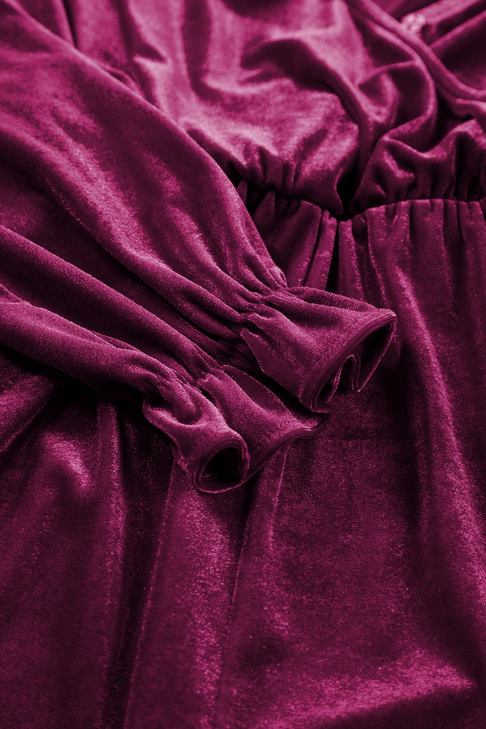Burgundy velvet romper with ruffled cuffs and cinched waist detail.