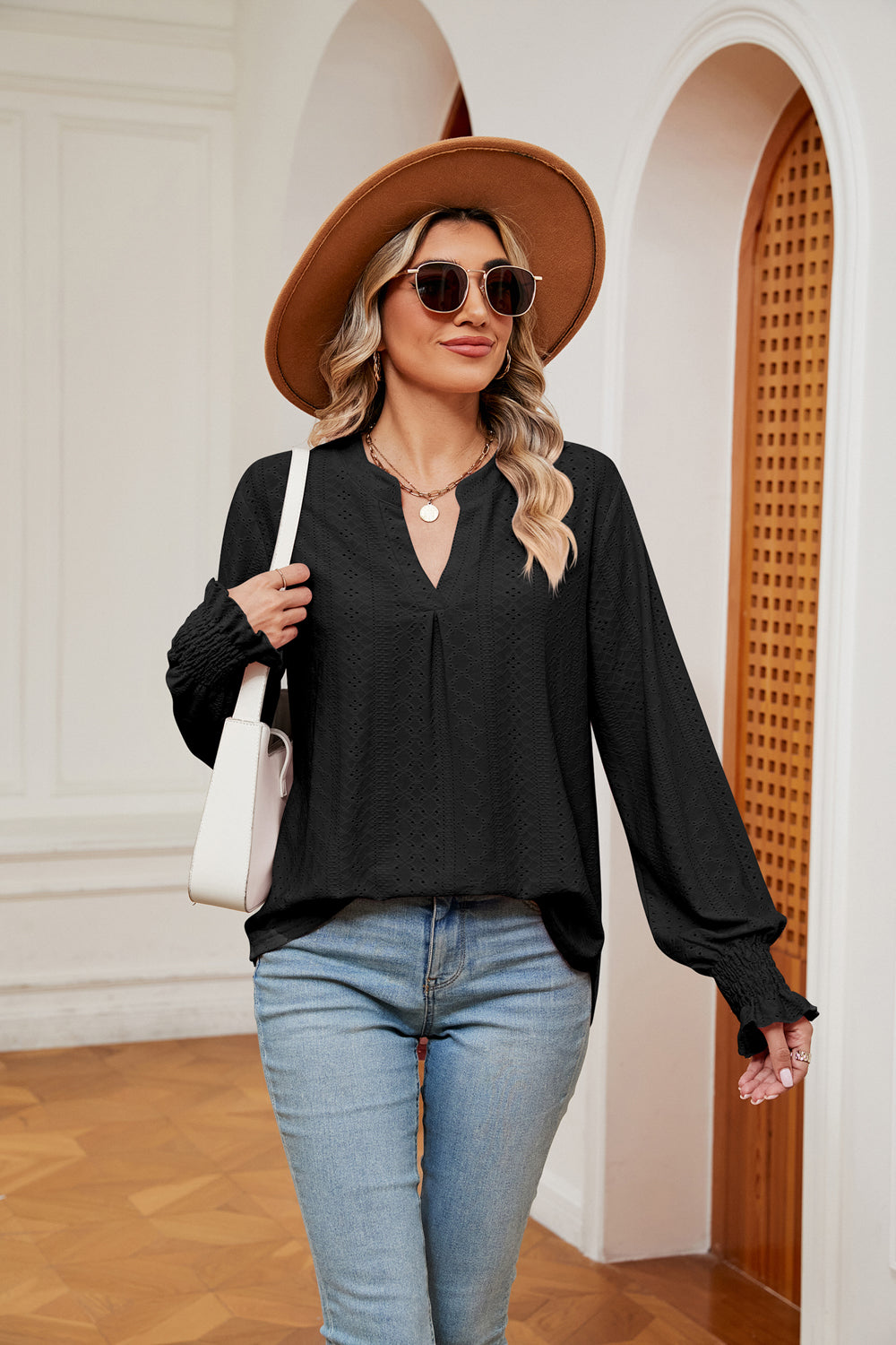 Black eyelet detail poet sleeve blouse with V-neck and smocked cuffs.