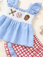Baby girl's blue cotton smocked top with baseball embroidery and red checkered shorts.