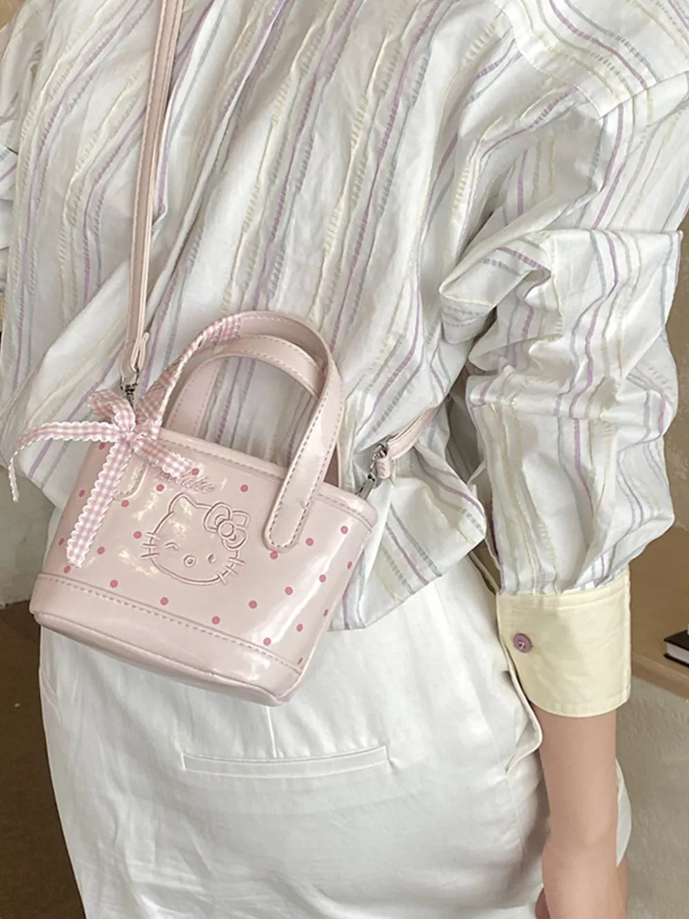 Charming mini crossbody bag in blush pink with Hello Kitty detail and bow.