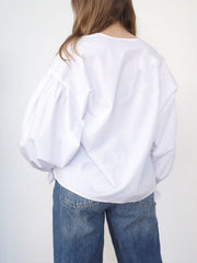 White long sleeve blouse with voluminous puff sleeves and a tie detail at the hem.