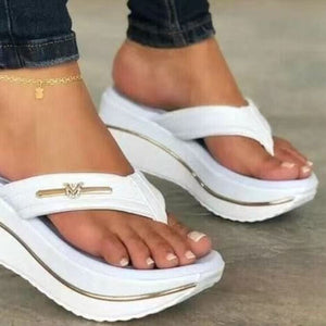White platform thong sandals with gold emblem detail and stacked sole.