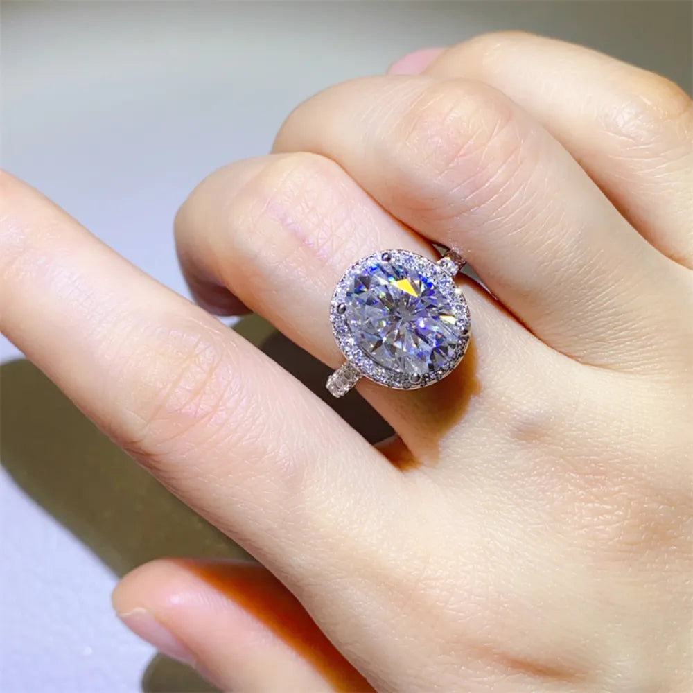 Silver oval halo moissanite engagement ring with a large center stone and diamond accents.