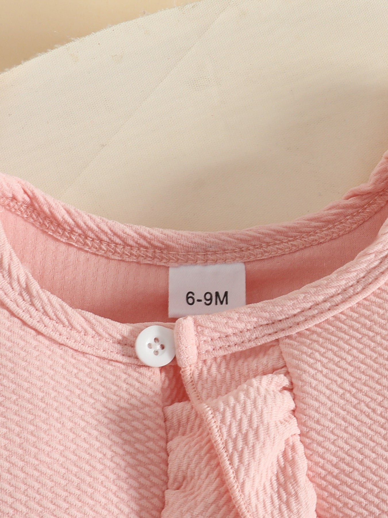 Pink baby dress and cardigan set with ruffle detail and button closure.