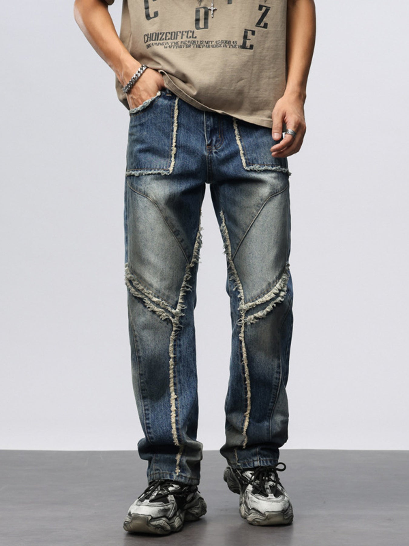 Men's wide leg jeans in blue denim with frayed hem details and patchwork design.