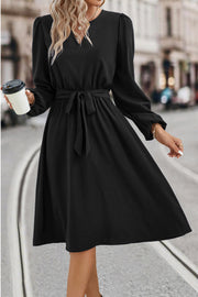 Black midi dress with poet sleeves, V-neck, and tie waist.