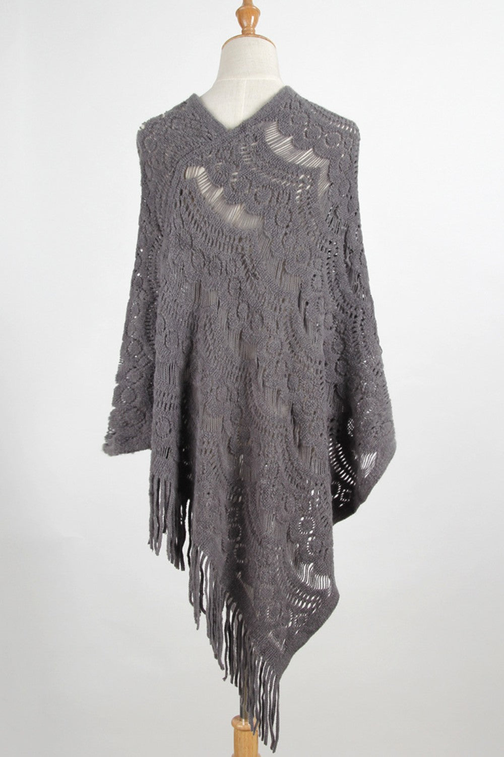 Dark gray crochet poncho with intricate openwork pattern and fringe detail.