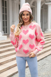 Blush pink knit pullover sweater with textured heart motif, crew neck, and long sleeves.